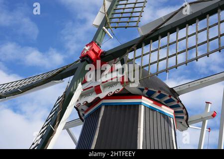 Typische holländische Windmühle im Winter mit gefrorenem Wasser und blauem Himmel mit einigen Wolken Stockfoto