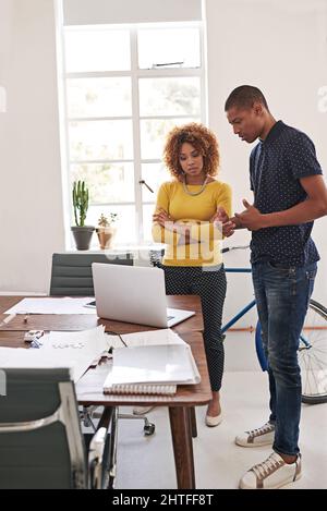 Welches gefällt Ihnen am besten? Aufnahme von Mitarbeitern, die in einem modernen Büro ein informelles Treffen mit einem Laptop abhalten. Stockfoto