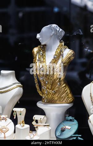 Schaufenster eines Juwelierladens mit einer riesigen Auswahl an goldenen Schmuckarmbändern, Ketten, Ringen und Ohrringen auf einem weiblichen Flachrelief Stockfoto