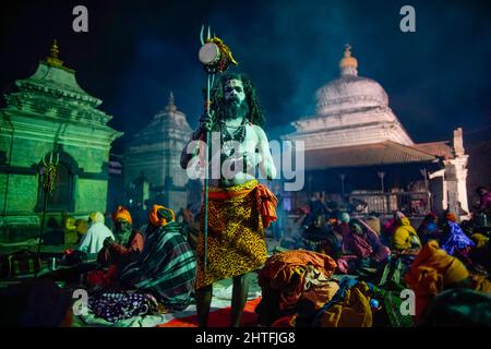 Kathmandu, Nepal. 28.. Februar 2022. Ein Sadhu, heilige Männer und Anhänger von Lord Shiva atmet Marihuana aus einem Chillum am Vorabend des Maha Shivaratri-Festivals im Pashupatinath-Tempel in Kathmandu aus. Tausende von Sadhus aus Indien und Nepal kommen, um das Maha Shivaratri-Fest zu feiern, indem sie Marihuana rauchen, ihre Körper mit Asche beschmieren und Gebete für den hinduistischen Gottheitsherrn Shiva anbieten. (Bild: © Skanda Gautam/ZUMA Press Wire) Stockfoto