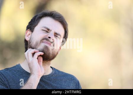 Überfordert Mann kratzt juckenden Bart im Freien
