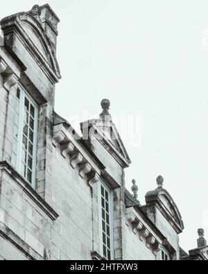 Vertikale Graustufenaufnahme eines alten Gebäudes mit einem Holzfenster Stockfoto