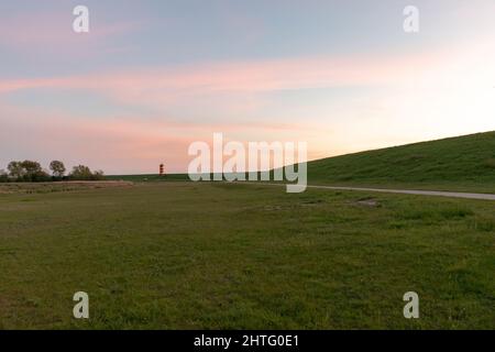 Vibrierend grüner Rasen mit Pilsum Leuchtturm in der Ferne Stockfoto