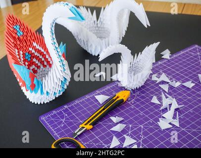 Nahaufnahme von bunten Origami-Schwanen auf einem schwarzen Schreibtisch Stockfoto