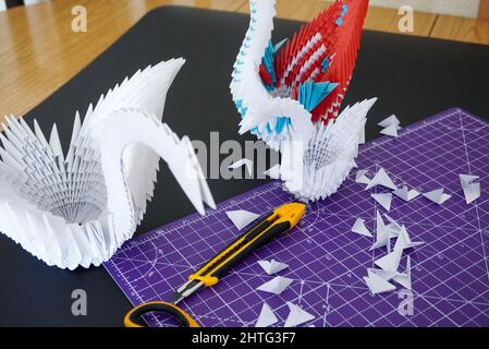 Nahaufnahme von bunten Origami-Schwanen auf einem schwarzen Schreibtisch Stockfoto