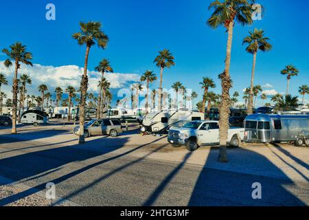 Wohnmobilstellplatz mit hohen Palmen, die in der Abendsonne lange Schatten werfen. Tonopah, Arizona, USA Stockfoto