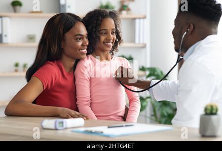 Lächelndes afroamerikanisches Mädchen, das einen Arzt in der Klinik besucht Stockfoto