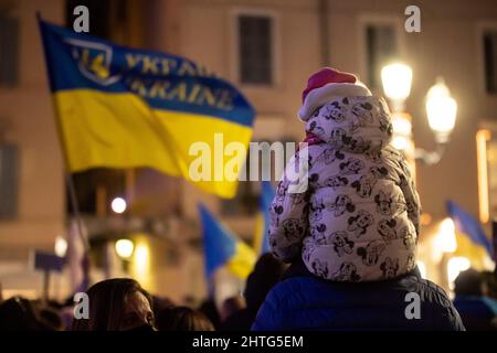 Brescia, Brescia, Italien. 28.. Februar 2022. Demonstration gegen den Krieg in der Ukraine ein Kind auf den Schultern seines Vaters auf der Piazza Loggia mit ukrainischen Fahnen (Foto: © Matteo Biatta/ZUMA Press Wire) Stockfoto