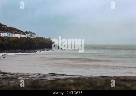 Wunderschöne Aussicht auf den Strand, die Irische See und die Cardigan Bay an der walisischen Küste in New Quay, Wales an einem bewölkten Tag Stockfoto