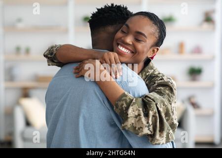 Nahaufnahme einer fröhlichen schwarzen Soldatin, die ihren Freund umarmt Stockfoto