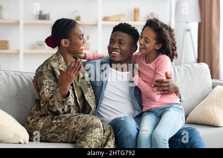 Fröhliche Familie sitzt auf der Couch, Mutter Soldat zurück aus dem Dienst Stockfoto