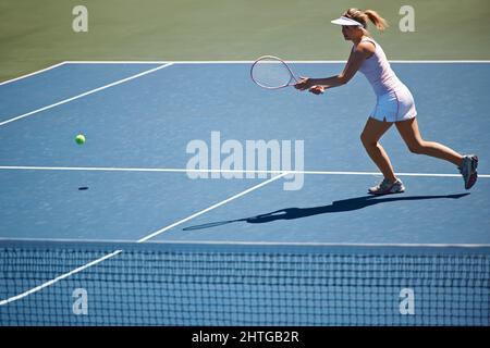 Ich habe es verstanden. Junge Frau spielt Tennis auf dem Platz. Stockfoto