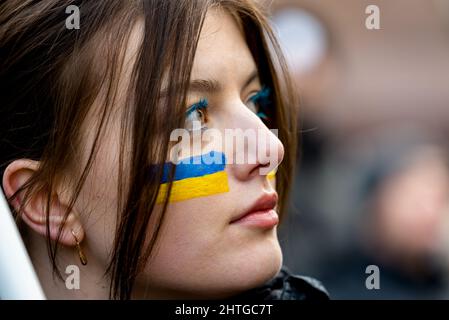 Warschau, 27. Februar 2022: Protest gegen den Krieg in der Ukraine und die russische Invasion. Porträt einer Frau mit gemalter ukrainischer Flagge. Stehe mit der Ukraine Stockfoto