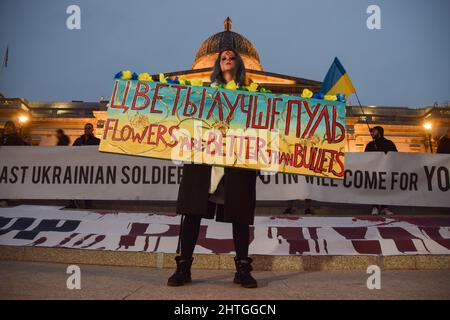 London, England, Großbritannien. 28.. Februar 2022. Hunderte von Menschen versammelten sich am sechsten Tag der Proteste auf dem Trafalgar Square, während der Krieg in der Ukraine andauert. Ein Protestler hält ein Schild mit der Aufschrift „Blumen und besser als Kugeln“. (Bild: © Vuk Valcic/ZUMA Press Wire) Stockfoto