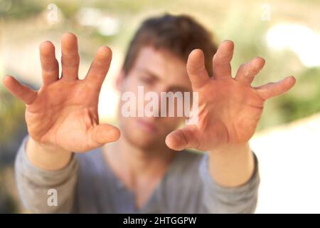 Kräftig harte Hände. Ein hübscher junger Mann hält seine gefühlsbefangten Hände hoch. Stockfoto
