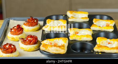 Frisches, hausgemachtes Gebäck. Mischung aus Blätterteig und Vorspeisen. Rosafarbter Pfefferoni-Kuchen. Gebäck mit Salami. Stockfoto