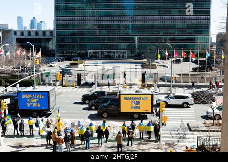 New York, NY, USA. 28.. Februar 2022. Pro-ukrainische Demonstranten sehen sich den Vereinten Nationen gegenüber, wenn sie auf der anderen Seite der First Avenue beleuchtete Schilder mit abwechselnd russischem und englischem Text tragen. New York, NY - 28. Februar 2022. Pro-ukrainische Demonstranten sehen sich den Vereinten Nationen gegenüber, wenn sie auf der anderen Seite der First Avenue beleuchtete Schilder mit abwechselnd russischem und englischem Text tragen. Diese, aus dem Russischen übersetzt, lautete „Stoppt Putins Krieg“ und „vereinigt euch um der Welt willen“. Quelle: Ed Lefkowicz/Alamy Live News Stockfoto