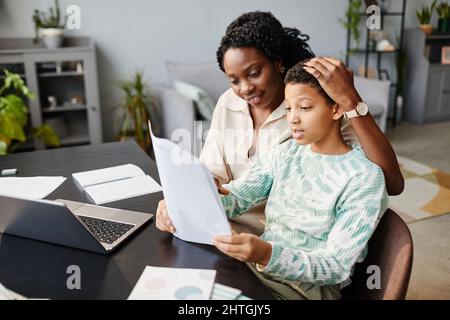 Porträt einer liebenden afroamerikanischen Mutter und Tochter, die zusammen zu Hause studiert und die Testergebnisse betrachtet Stockfoto