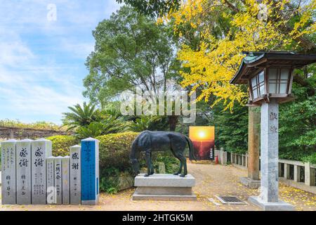 kyushu, japan - 08 2021. dezember: Steinlaterne vor einer göttlichen Shinme-Pferdebronzstatue, die dem japanischen Miyajidake-Schrein mit einem Poster von angeboten wird Stockfoto