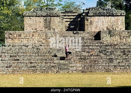 Yoga Pose auf dem Ball Court in den Copan Mayan Ruinas, Honduras Stockfoto