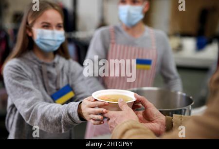 Freiwillige servieren heiße Suppe für ukrainische Migranten im Flüchtlingszentrum, russisches Konfliktkonzept. Stockfoto