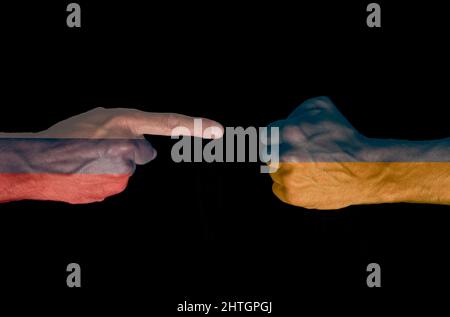 Abbildung einer Hand mit der russischen Flagge, die auf eine Faust zeigt, mit der ukrainischen Flagge, die auf schwarzem Hintergrund gedruckt ist. Bewaffneter Konflikt Stockfoto