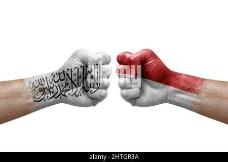 Zwei Hände schlagen sich gegenseitig auf weißem Hintergrund zu. Länderflaggen bemalten Fäuste, Konfliktkrisenkonzept zwischen afghanistan und monaco Stockfoto