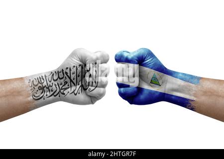 Zwei Hände schlagen sich gegenseitig auf weißem Hintergrund zu. Länderflaggen bemalten Fäuste, Konfliktkrisenkonzept zwischen afghanistan und nicaragua Stockfoto