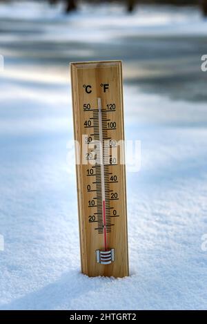 Das Quecksilberthermometer aus Holz, das auf Schnee hängt, weist niedrige Temperaturen auf. Stockfoto