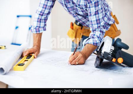Architekt arbeitet an der Blaupause. Nahaufnahme eines vielbeschäftigten Architekten, der mit Hilfe von Level und Bleistift an der Blaupause arbeitet. Stockfoto