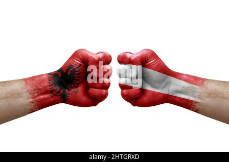Zwei Hände schlagen sich gegenseitig auf weißem Hintergrund zu. Länderflaggen bemalten Fäuste, Konfliktkrisenkonzept zwischen albanien und österreich Stockfoto