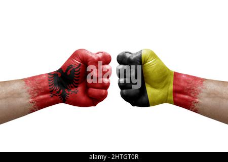 Zwei Hände schlagen sich gegenseitig auf weißem Hintergrund zu. Länderflaggen bemalten Fäuste, Konfliktkrisenkonzept zwischen albanien und belgien Stockfoto