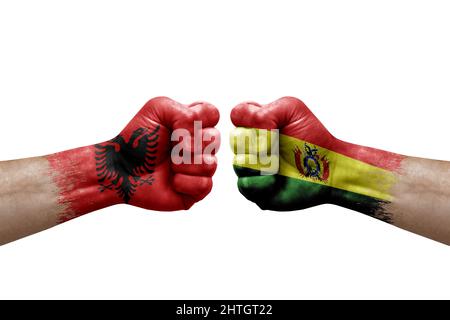 Zwei Hände schlagen sich gegenseitig auf weißem Hintergrund zu. Länderflaggen bemalten Fäuste, Konfliktkrisenkonzept zwischen albanien und bolivien Stockfoto