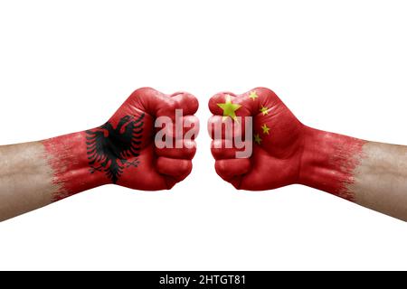 Zwei Hände schlagen sich gegenseitig auf weißem Hintergrund zu. Länderflaggen bemalten Fäuste, Konfliktkrisenkonzept zwischen albanien und china Stockfoto