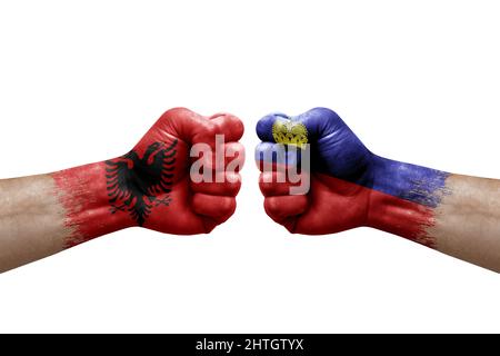 Zwei Hände schlagen sich gegenseitig auf weißem Hintergrund zu. Länderflaggen bemalten Fäuste, Konfliktkrisenkonzept zwischen albanien und liechtenstein Stockfoto