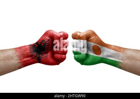 Zwei Hände schlagen sich gegenseitig auf weißem Hintergrund zu. Länderflaggen bemalten Fäuste, Konfliktkrisenkonzept zwischen albanien und niger Stockfoto
