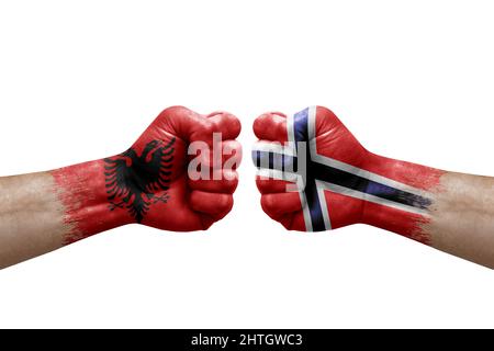 Zwei Hände schlagen sich gegenseitig auf weißem Hintergrund zu. Länderflaggen bemalten Fäuste, Konfliktkrisenkonzept zwischen albanien und norwegen Stockfoto
