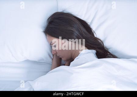Draufsicht auf gestresste und depressive Frau, die im Bett liegt. Frau fühlt sich schlecht, verzweifelt und hilflos. Depression in der psychischen Gesundheit Stockfoto