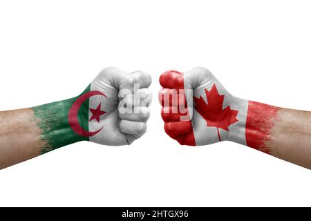Zwei Hände schlagen sich gegenseitig auf weißem Hintergrund zu. Länderflaggen bemalten Fäuste, Konfliktkrisenkonzept zwischen algerien und kanada Stockfoto