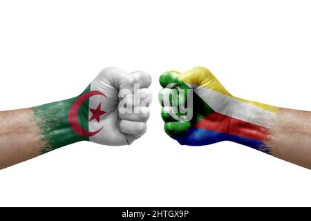 Zwei Hände schlagen sich gegenseitig auf weißem Hintergrund zu. Länderflaggen bemalten Fäuste, Konfliktkrisenkonzept zwischen algerien und komoren Stockfoto