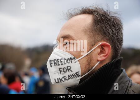 Ljubljana, Slowenien. 28.. Februar 2022. Ein Protestler trägt eine Gesichtsmaske mit einem Schild zur Unterstützung der Ukraine während eines Protestes gegen die russische Invasion in der Ukraine in Ljubljana.nach der russischen Invasion in der Ukraine versammelten sich in der slowenischen Hauptstadt erneut Menschen, um gegen den Krieg zu protestieren. Kredit: SOPA Images Limited/Alamy Live Nachrichten Stockfoto