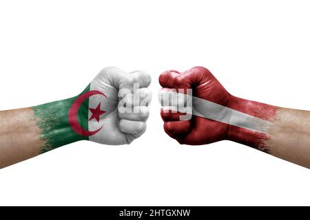 Zwei Hände schlagen sich gegenseitig auf weißem Hintergrund zu. Länderflaggen bemalten Fäuste, Konfliktkrisenkonzept zwischen algerien und lettland Stockfoto