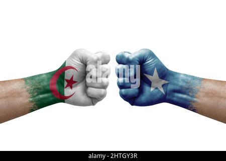 Zwei Hände schlagen sich gegenseitig auf weißem Hintergrund zu. Länderflaggen bemalten Fäuste, Konfliktkrisenkonzept zwischen algerien und somalia Stockfoto