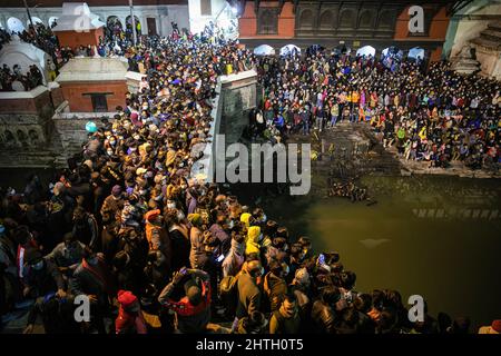 Kathmandu, Nepal. 28.. Februar 2022. Hindu-Anhänger versammeln sich, um die religiösen Rituale zu beobachten und am Vorabend des Maha Shivaratri-Festivals in den Räumlichkeiten des Pashupatinath-Tempels zu tanzen. Kredit: SOPA Images Limited/Alamy Live Nachrichten Stockfoto