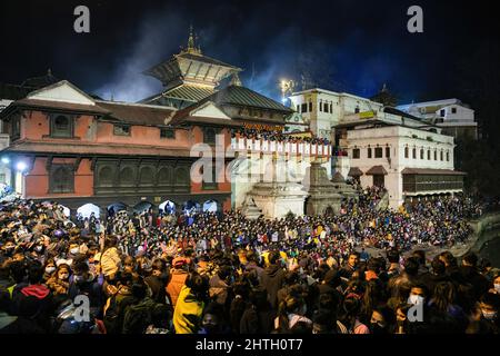 Kathmandu, Nepal. 28.. Februar 2022. Hindu-Anhänger versammeln sich, um die religiösen Rituale zu beobachten und am Vorabend des Maha Shivaratri-Festivals in den Räumlichkeiten des Pashupatinath-Tempels zu tanzen. Kredit: SOPA Images Limited/Alamy Live Nachrichten Stockfoto