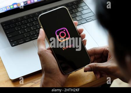 CHIANG MAI, THAILAND - 26 2022. FEBRUAR: Ein Mann hält Apple iPhone 13 mit Instagram-Anwendung auf dem Bildschirm im Café. Instagram von meta ist ein Foto Stockfoto
