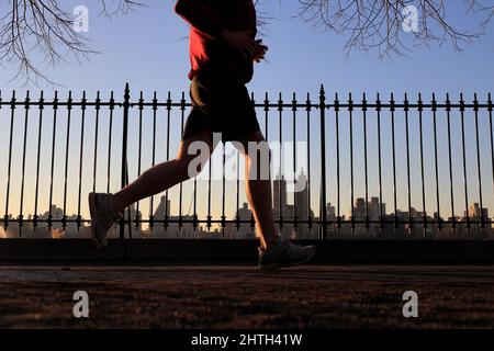 Mann, der alleine den Weg des Central Park Reservoir mit der Skyline des Central Park West im Hintergrund läuft.New York City.NY.USA Stockfoto