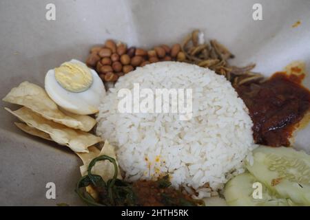 Nasi Lemak ist eine malaiische Küche, die aus Malaysia stammt und aus duftendem Reis besteht, der in Kokosmilch und Pandanblatt gekocht wird. Stockfoto