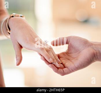 Sie markieren ihre wahre Liebe. Nahaufnahme eines Mannes, der einen Verlobungsring auf den Finger seiner Verlobten legt. Stockfoto