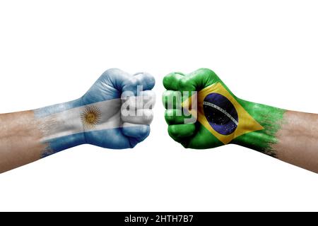 Zwei Hände schlagen sich gegenseitig auf weißem Hintergrund zu. Länderflaggen bemalten Fäuste, Konfliktkrisenkonzept zwischen argentinien und brasilien Stockfoto